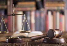 Gavel and scales on desk with books.