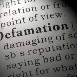 Close-up of the word Defamation in a dictionary.