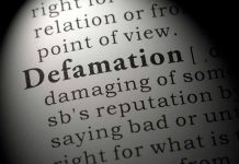 Close-up of the word Defamation in a dictionary.