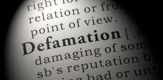 Close-up of the word Defamation in a dictionary.