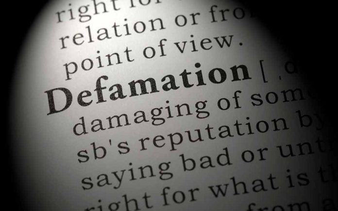 Close-up of the word Defamation in a dictionary.