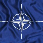 NATO flag with blue background and white compass.