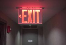 Red illuminated exit sign in a hallway.