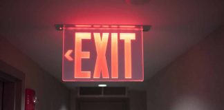 Red illuminated exit sign in a hallway.