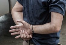 Person in handcuffs with hands behind back.