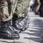 Soldiers in uniform and boots standing in formation.