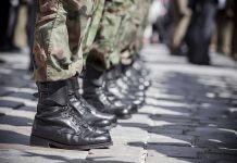 Soldiers in uniform and boots standing in formation.