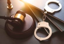 Gavel, books, and handcuffs on a table.