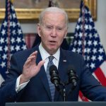 Biden speaking at podium with American flags behind.