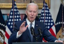 Biden speaking at podium with American flags behind.