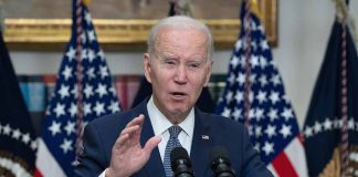 Biden speaking at podium with American flags behind.