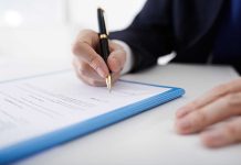 Person signing a document with a black pen.