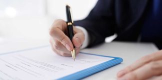 Person signing a document with a black pen.