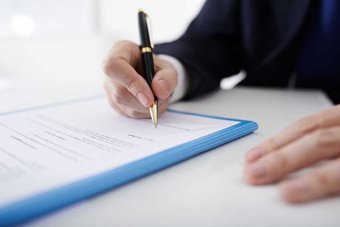 Person signing a document with a black pen.