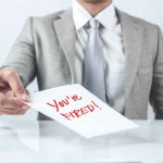 Person handing a paper with "You're Fired!" text.