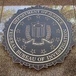 FBI seal on marble wall in daylight.