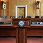 Empty U.S. Senate hearing room with wooden furniture.