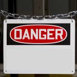 Danger sign hanging on metal chain.