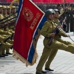 Soldiers marching with rifles and a red flag