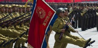 Soldiers marching with rifles and a red flag