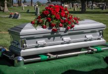 Silver casket with rose bouquet in a cemetery.