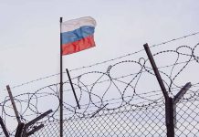 Russian flag behind barbed wire fence skyward view