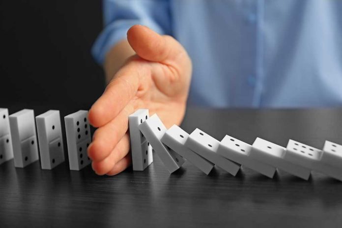 Hand stopping falling row of dominoes.