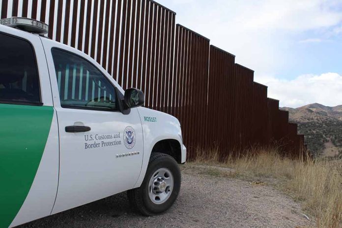 Border protection vehicle near a large metal fence.