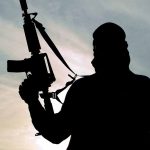 Silhouette of person holding a rifle.