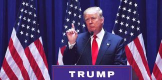 Man speaking at podium with American flags behind