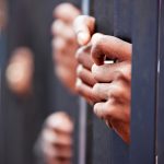 Hands gripping metal bars in focus