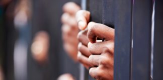 Hands gripping metal bars in focus