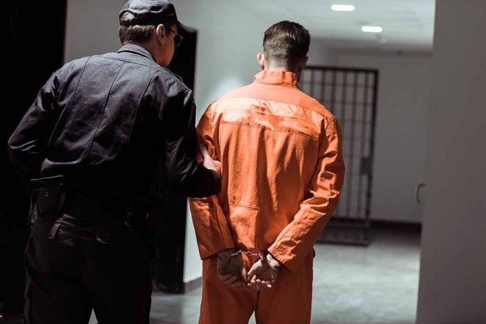 1030254055 featured image Policeman escorting handcuffed prisoner in orange jumpsuit