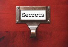 Metal label holder saying Secrets on wood background