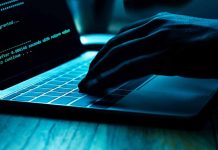 Hand typing on laptop with code on screen