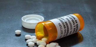 Open pill bottle with white tablets spilled out
