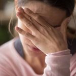 Woman covering face with hand looking stressed