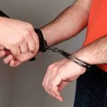 Person being handcuffed wearing orange shirt jeans