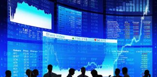 Silhouetted people in front of stock market displays