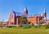 Large red brick building with turrets and green lawn