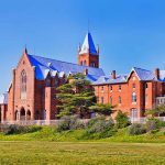 Large red brick building with turrets and green lawn