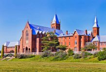 Large red brick building with turrets and green lawn