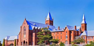 Large red brick building with turrets and green lawn