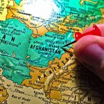 Hand placing pin on map of Afghanistan
