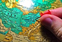 Hand placing pin on map of Afghanistan
