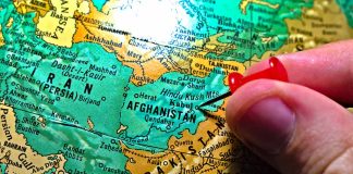 Hand placing pin on map of Afghanistan