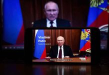 Man speaking on screen with Russian flag background