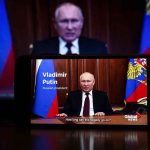Putin speaking on screen with Russian flag background
