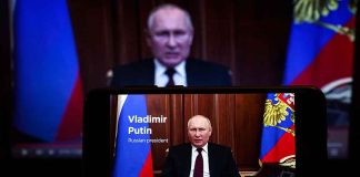 Putin speaking on screen with Russian flag background