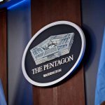 The Pentagon emblem between two flags